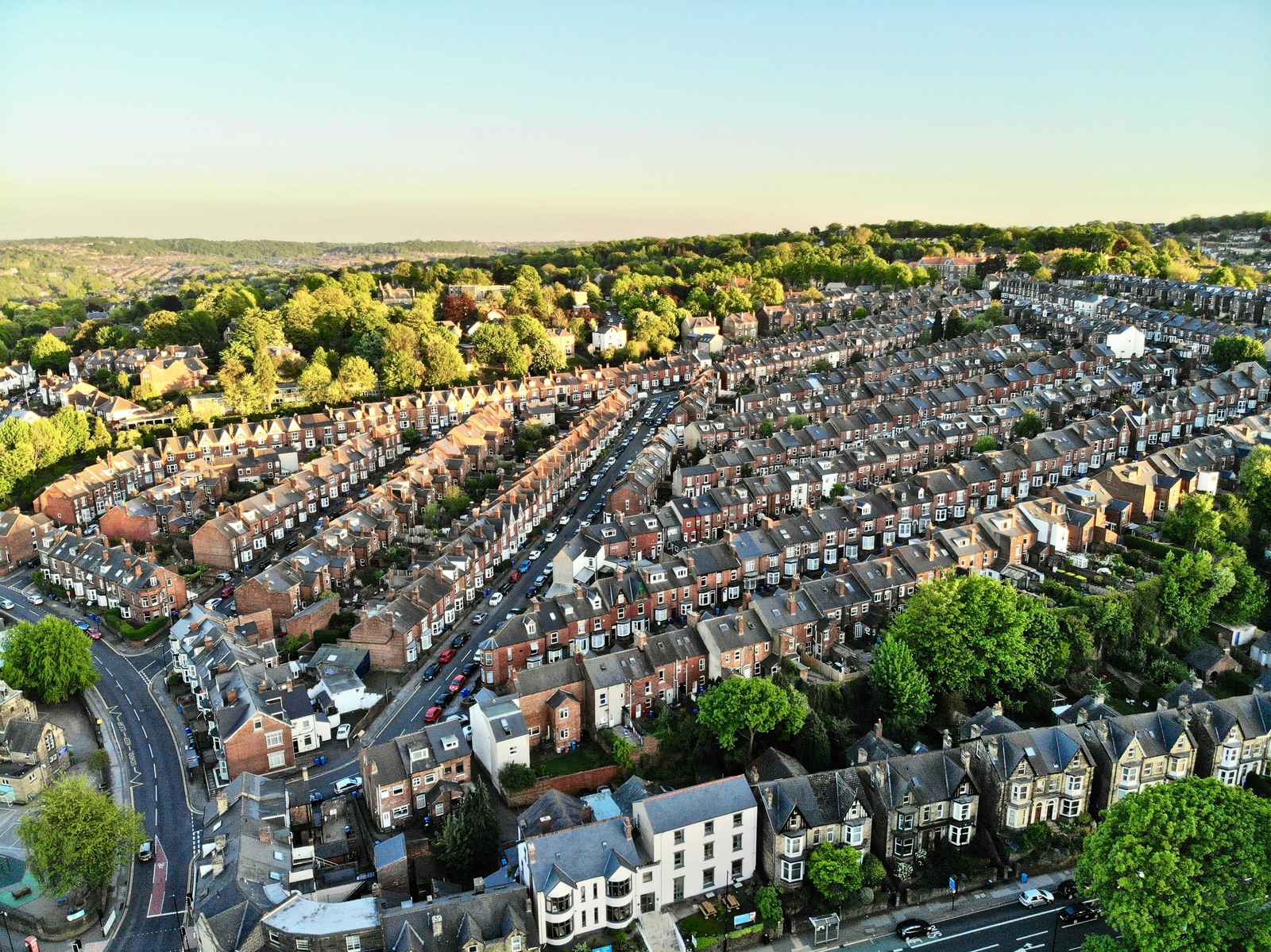 An aerial view of a residential area with many houses and trees, and a road winding through the neighbourhood